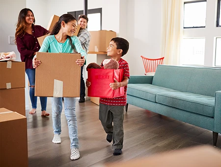 Family carrying boxes into new home